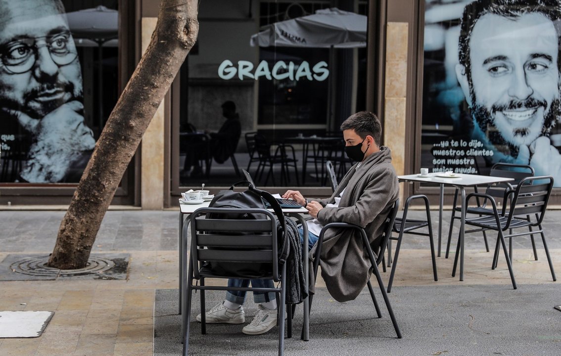 Un joven trabaja con su ordenador portátil en una terraza el primer día de la apertura de la hostelería en Valencia, Comunidad Valenciana (España), a 1 de marzo de 2021. Coincidiendo con el inicio de la desescalada en la región, la hostelería de la Comuni